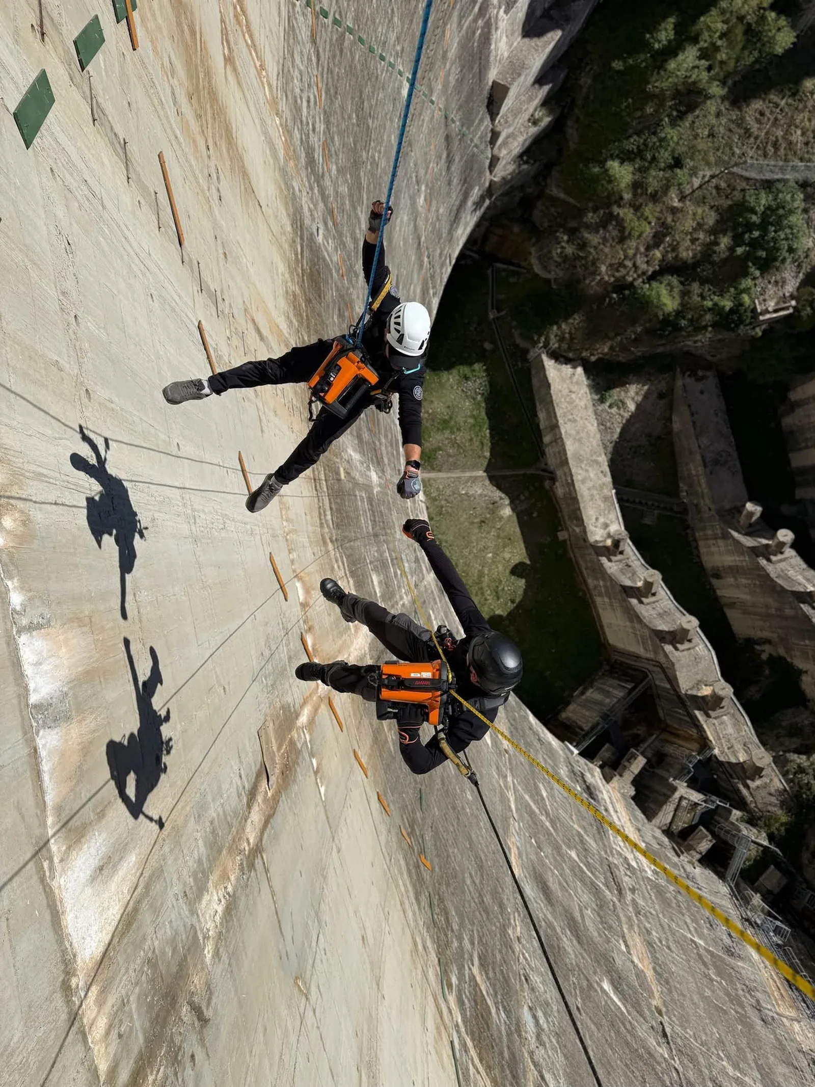 Dos técnicos de Solutions Vertical descolgados con cuerdas en la pared de una presa de hormigón