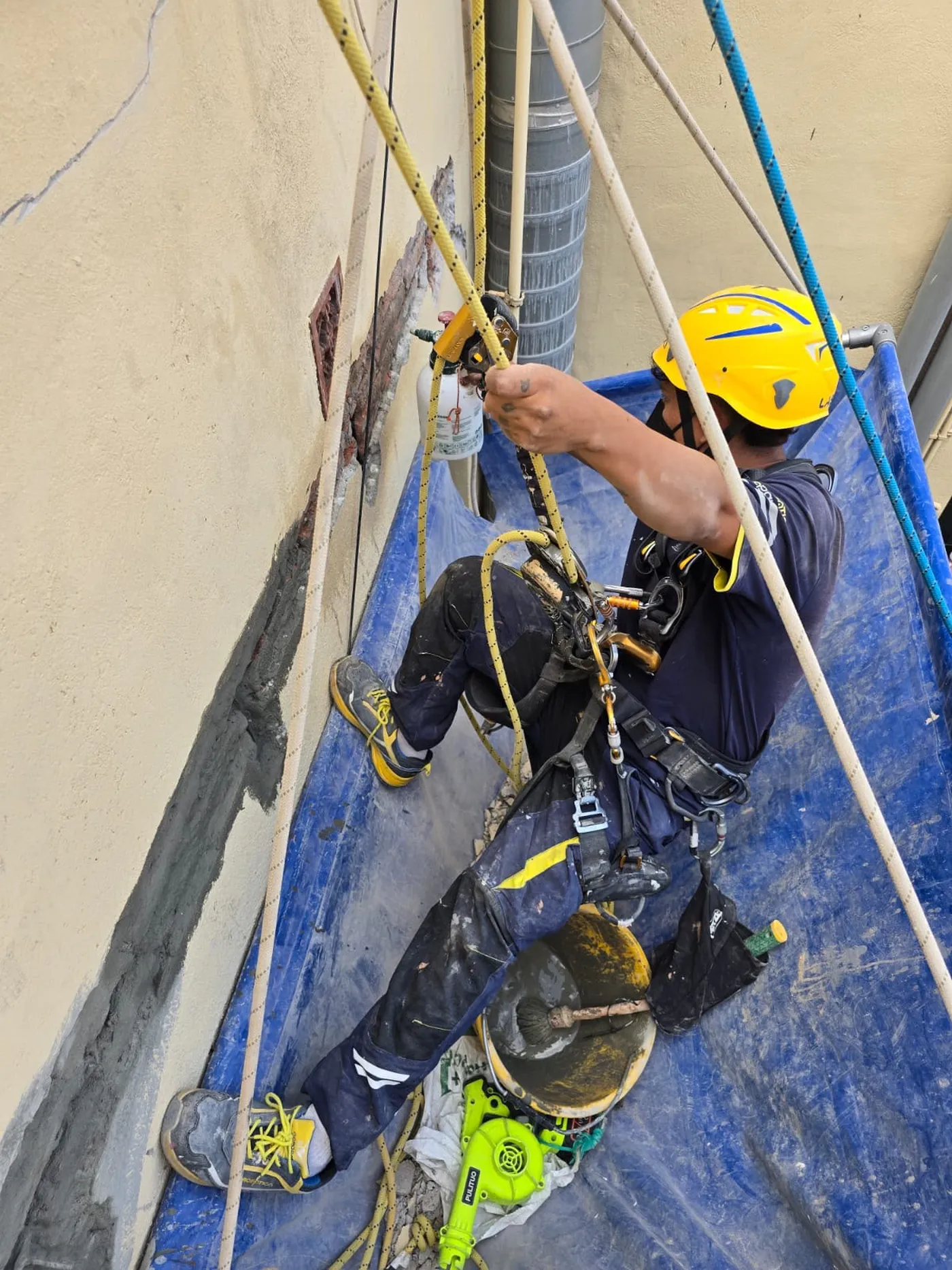Técnico descolgado con cuerdas trabajando sobre la fachada de un edificio